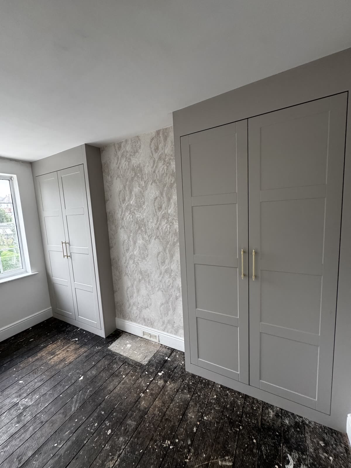 Fitted alcove wardrobes either side of a chimney breast with four-panel doors and brass bar handles