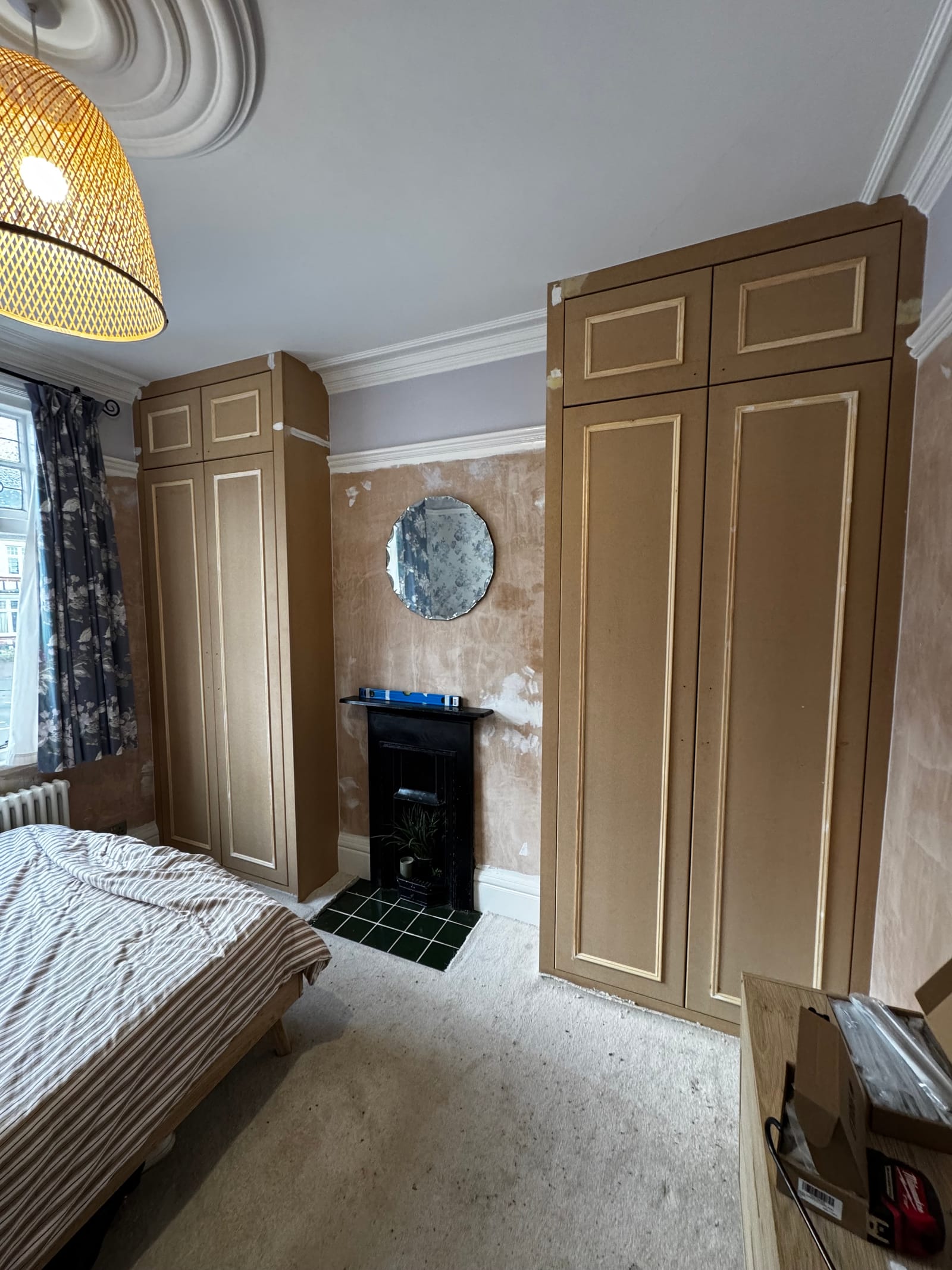 Period bedroom fitted wardrobe with classic raised cream panel doors above a fireplace