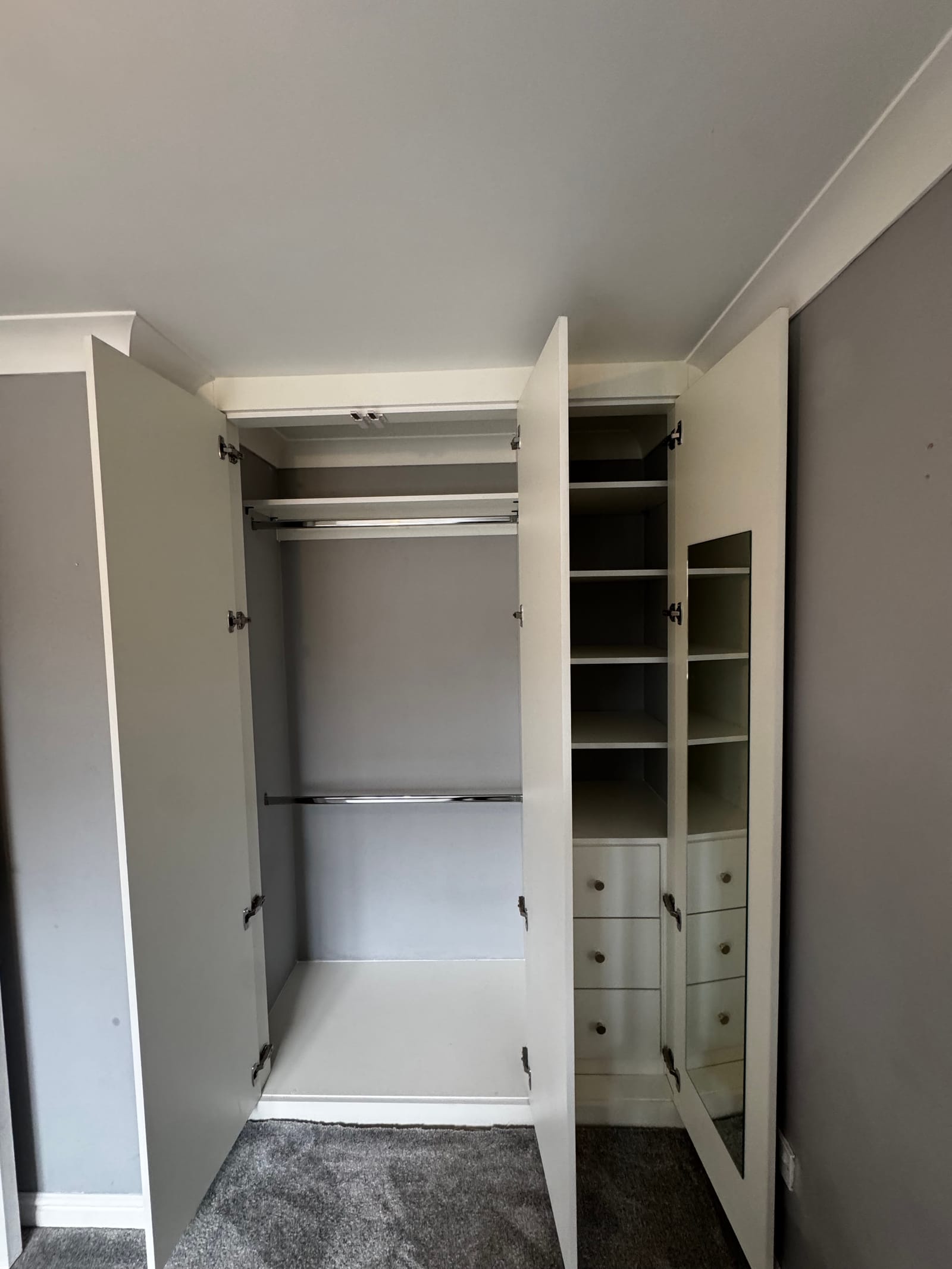 Interior of a bespoke fitted wardrobe with chrome hanging rails and adjustable shelving