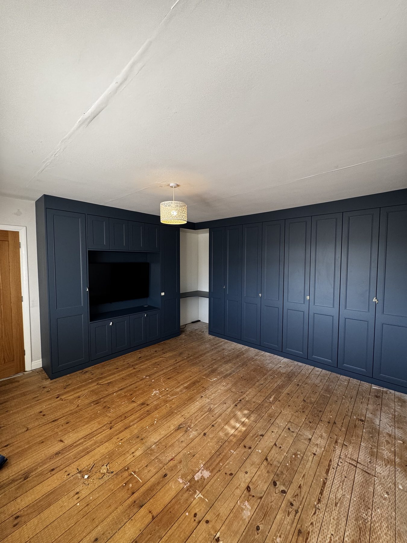 Floor-to-ceiling Alby Blue fitted wardrobes with matching media wall in a Birmingham bedroom